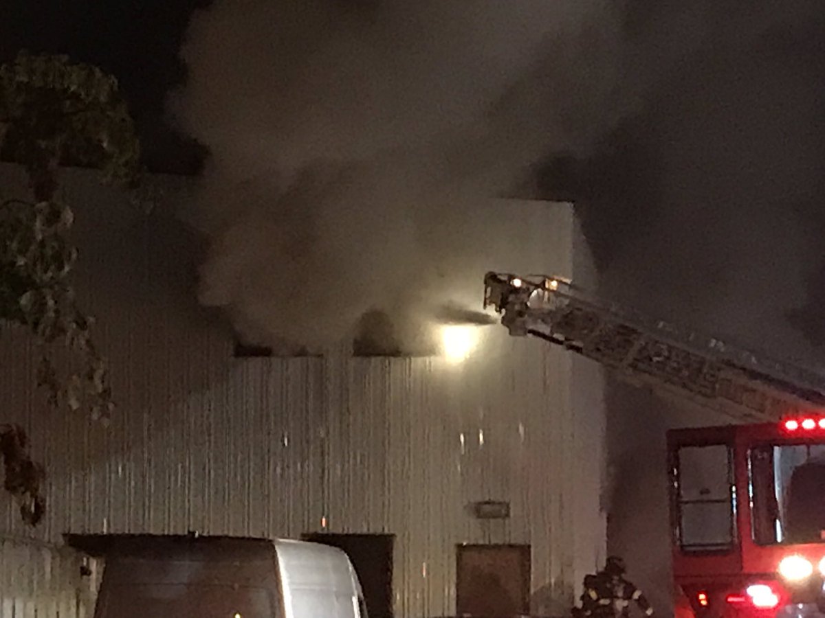 Fire in a warehouse in Ballard. @SeattleFire is attacking it with several hoses and locations. They are getting into the building with saws and ladder   