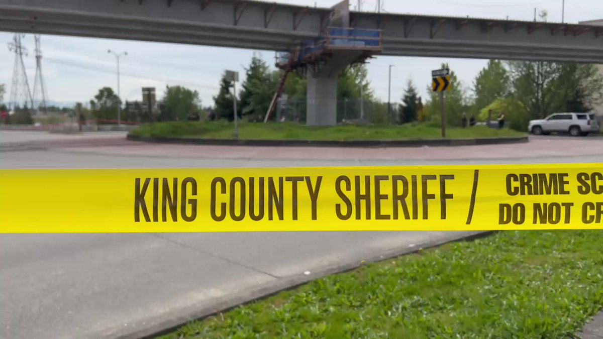 Crime scene tape wraps around this entire roundabout just off I-5.  You can see a number of King Co Sheriff deputies there in the distance. Squad cars are scattered all over.